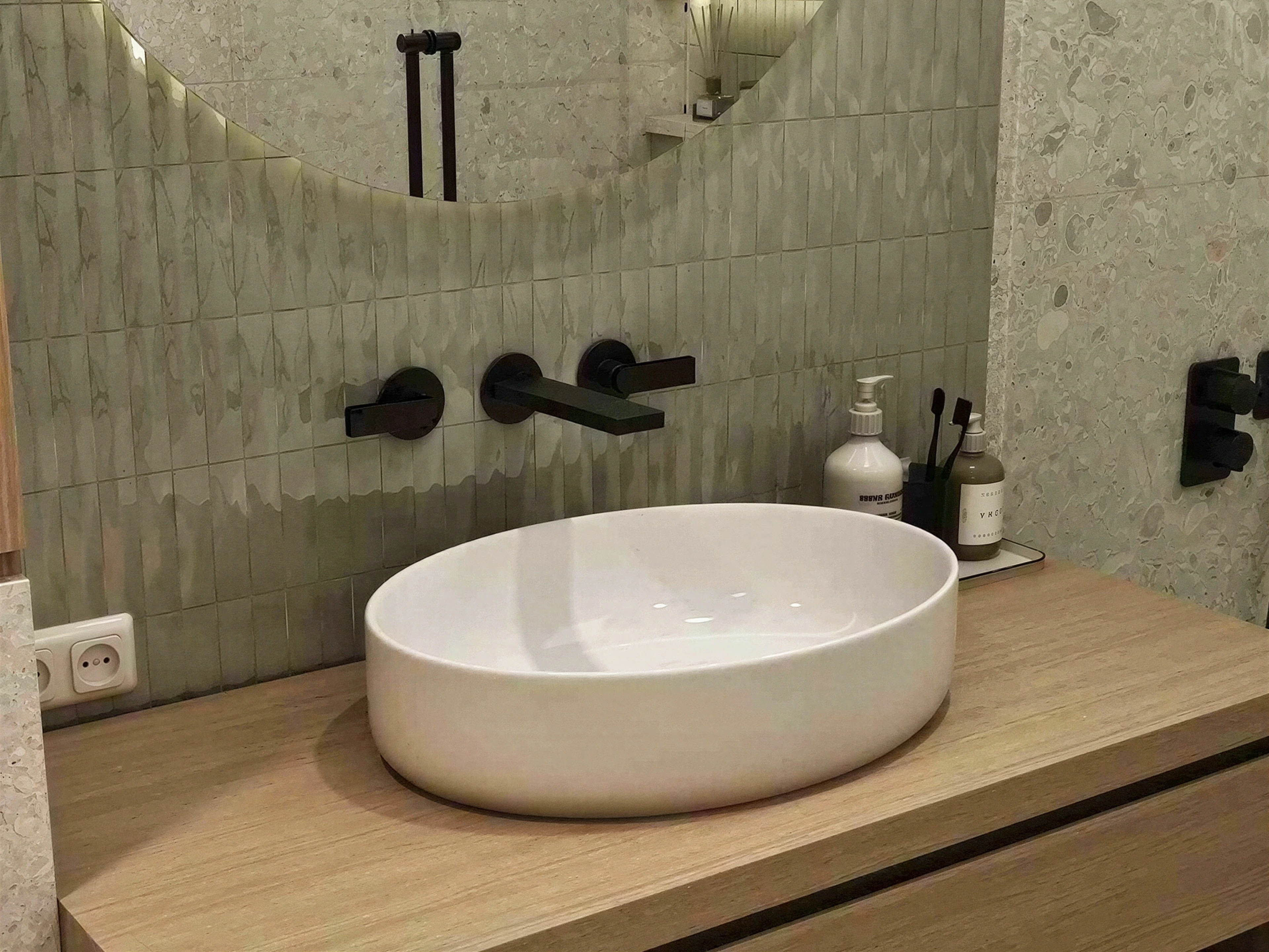 Close view of a vessel basin and black wall-mounted fittings.
