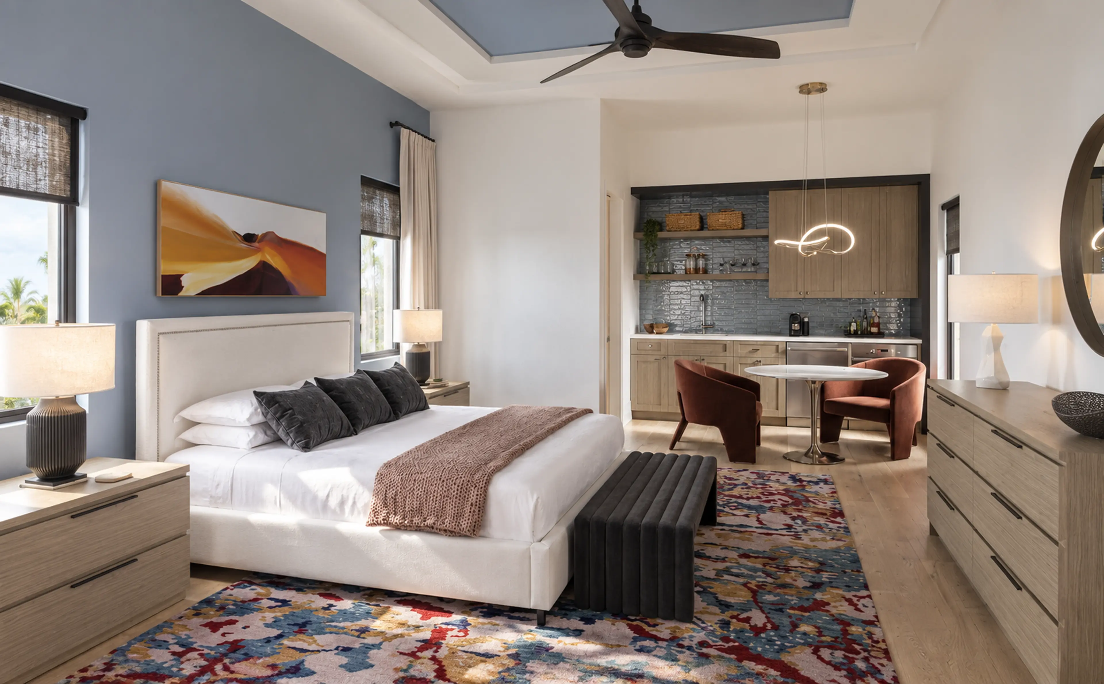 Guest suite with a pale bed, beverage bar and patterned rug.