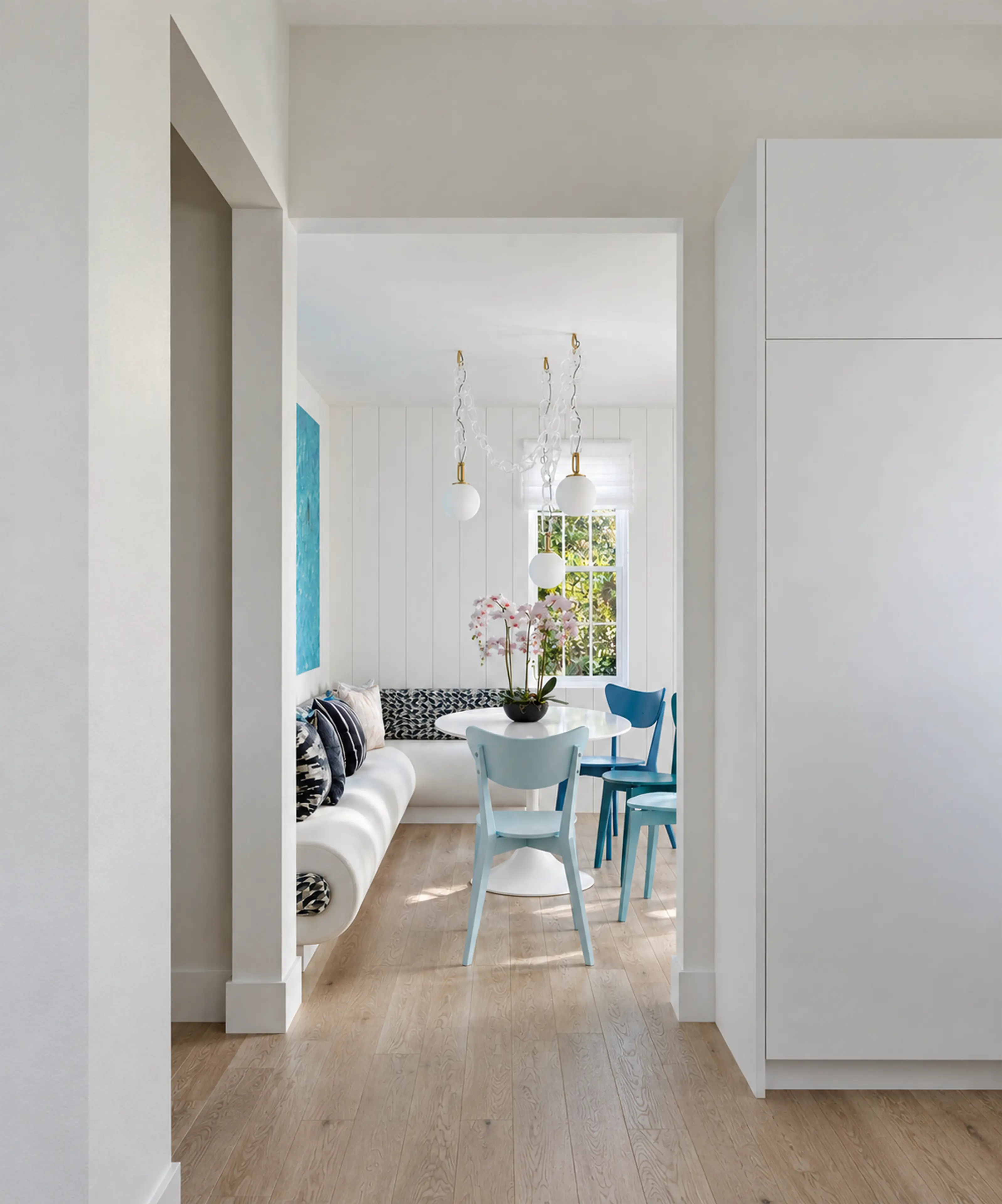 Photographic hallway view into a bright blue-and-white breakfast nook.